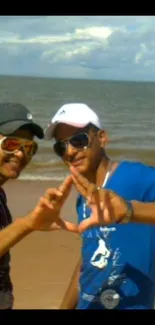 Two friends on a sunny beach creating a heart shape with their hands.