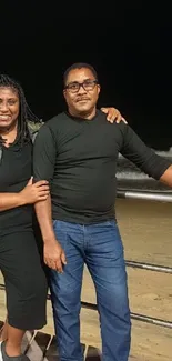 Couple enjoying a night by the beach with ocean waves in the background.