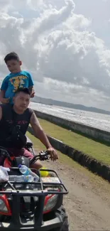 Father and son ride quad bike by the beach.