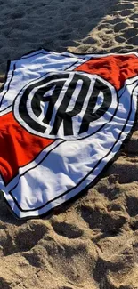 Beach sand with a logo towel spread under sunlight.