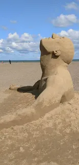 Sand sculpture on a beach under a blue sky.