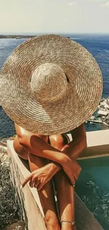 Woman in sunhat overlooks ocean with pool, capturing a serene coastal vibe.