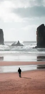 Solitary figure on a serene beach with towering rocks.