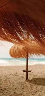 Straw umbrella on a sandy beach with ocean waves in the background.