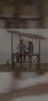 Friends enjoying a serene sunset on a beach under a rustic shelter.