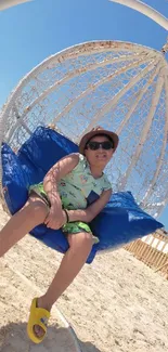 Person relaxing in a rattan swing at a sunny beach.