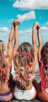 Three women with floral hair at beach, blue sky overhead.