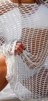 Person in a white mesh cover by the beach, with ocean view.