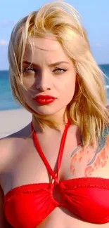 Blonde model in red bikini on beach with ocean backdrop.