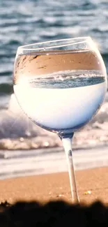 Wine glass at the beach reflecting ocean waves.