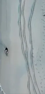 Aerial view of a sandy beach path with a lone walker.