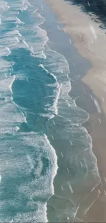 Aerial view of beach waves meeting the sandy shore in stunning blue hues.