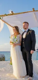 Couple weds under a floral arch at a beach ceremony.