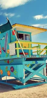 Vibrant lifeguard tower on sunny sandy beach under blue sky.