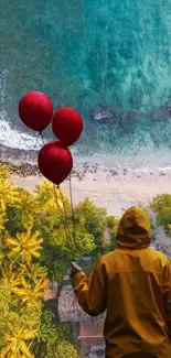 Aerial view of a beach with figure holding red balloons.