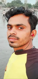 Beachside portrait with headphones and yellow shirt on a calm evening.