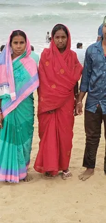 Family standing on sandy beach in colorful attire.