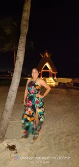 Smiling woman in tropical dress on a moonlit beach setting.