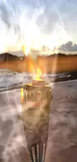 Torch glowing on the beach at sunset with a serene coastal backdrop.