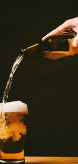 Hand pouring beer into a glass on a wooden table.