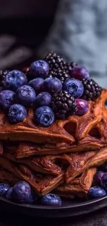 Stack of waffles topped with blueberries and blackberries.