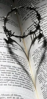 Open Bible with crown of thorns casting a heart-shaped shadow in black and white.