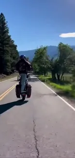 Biker riding on a scenic open road surrounded by nature.