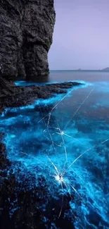 Bioluminescent blue waves illuminate rocky shore under twilight sky.