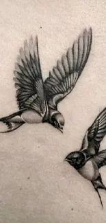 Tattoo of two birds on skin in grey ink.