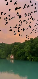 Silhouetted birds flying over a serene lake with lush green trees and a pastel sky.