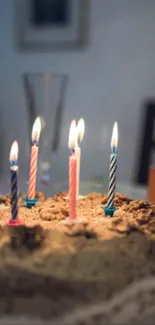 Vibrant birthday cake with lit candles in a festive setting.