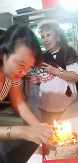 Women enjoying a birthday party with a candle-lit cake.