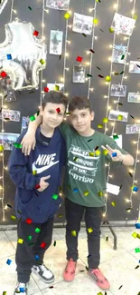 Two young boys celebrating a birthday with lights and photos.