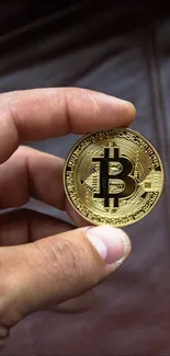 Close-up of a hand holding a Bitcoin coin highlighting its detailed design.