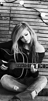 Black and white photo of a guitarist sitting with guitar.