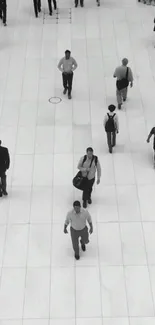 Black and white image of people walking on a tiled plaza.