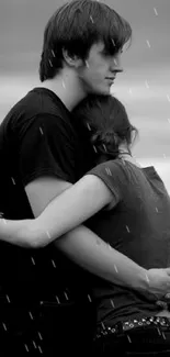 Black and white photo of couple embracing by the sea.