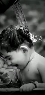 Smiling baby enjoying water splash in black and white.