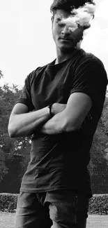 Black and white portrait of a young man in a park posing with arms crossed.