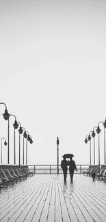 Black and white pier with a couple walking under street lamps.