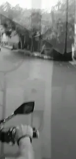 Black and white image of a person riding a motorcycle on an empty street.