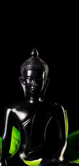 Black Buddha statue surrounded by green leaves on a dark background.