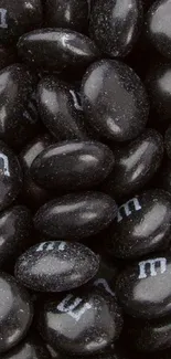 Black candies with 'm' branding for a stylish phone wallpaper.