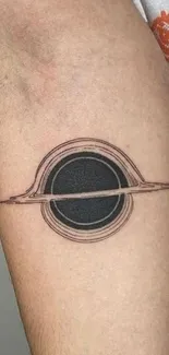 Minimalist black hole tattoo on arm.