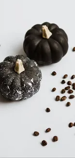 Black pumpkins with coffee beans on a light surface.