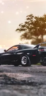 Black sports car parked at sunset with sky and trees.