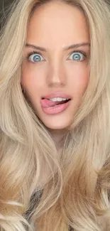 Blonde person with playful expression and clear eyes.