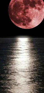 Blood moon reflecting over a calm ocean under a dark night sky.