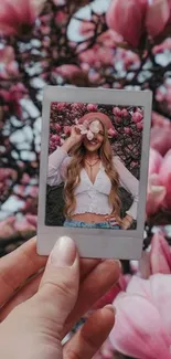 Hand holding polaroid with pink blooms background.