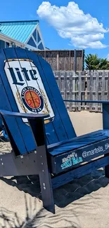 Giant blue beach chair with Miller Lite logo on sandy beach.